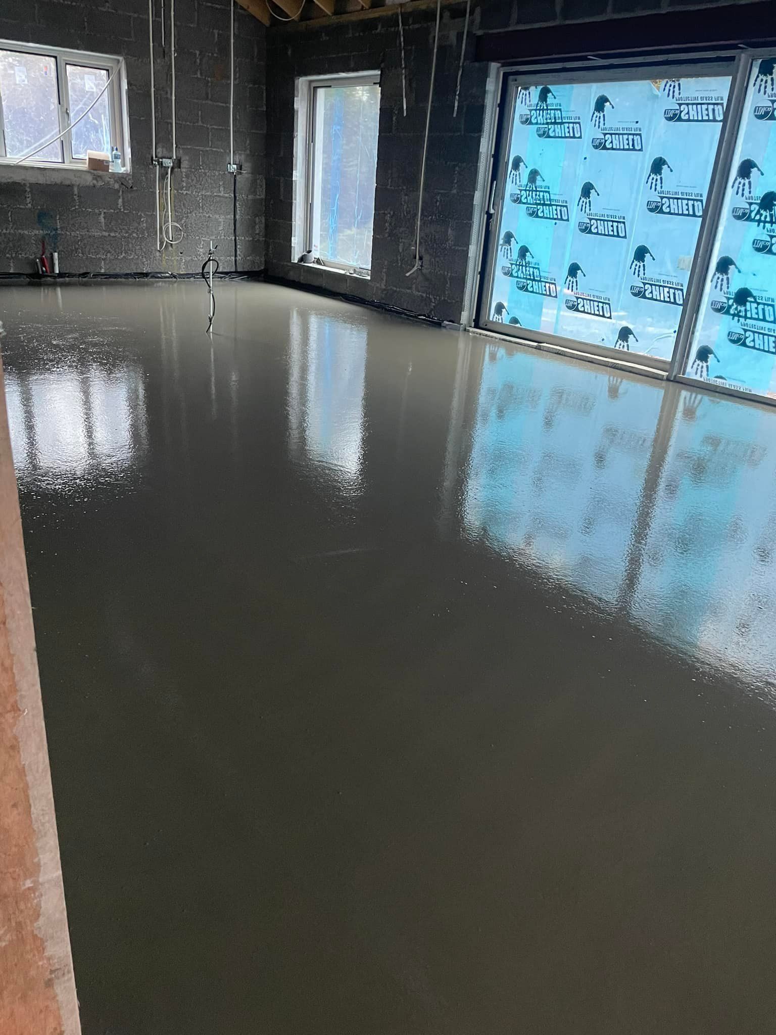 A room with a concrete floor and a lot of windows.