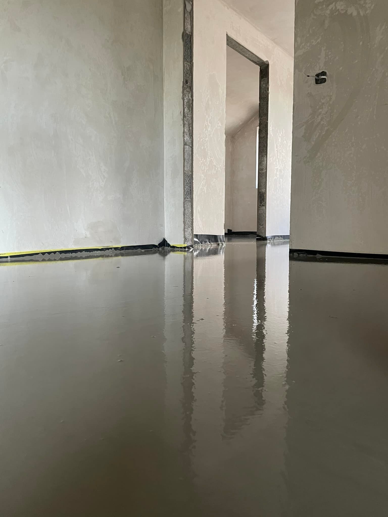 There is a reflection of a door in the floor of a building under construction.