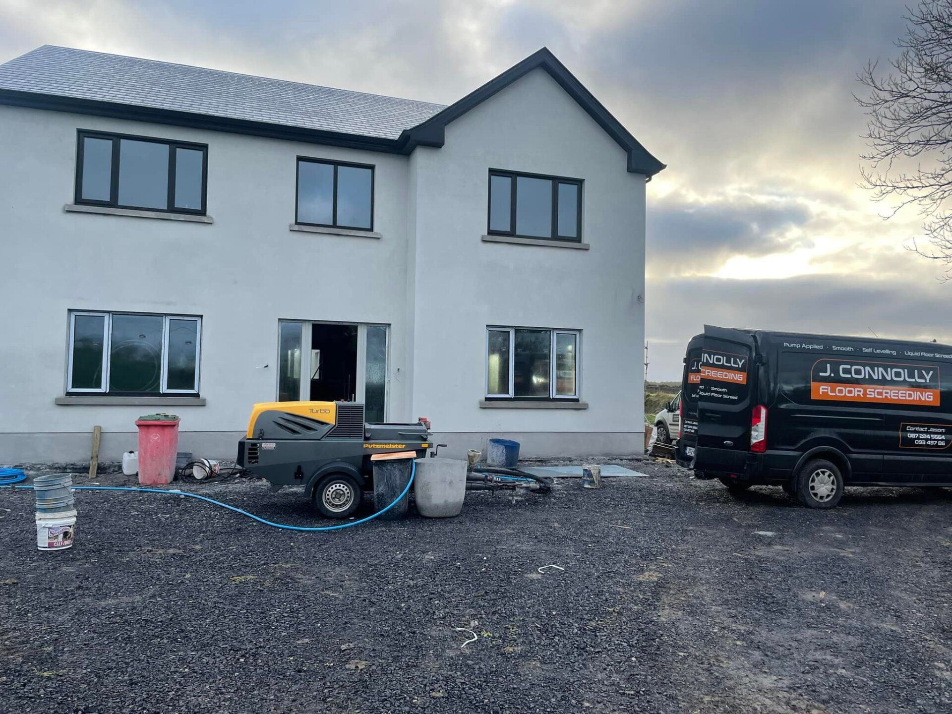 A large white house with a black van parked in front of it.