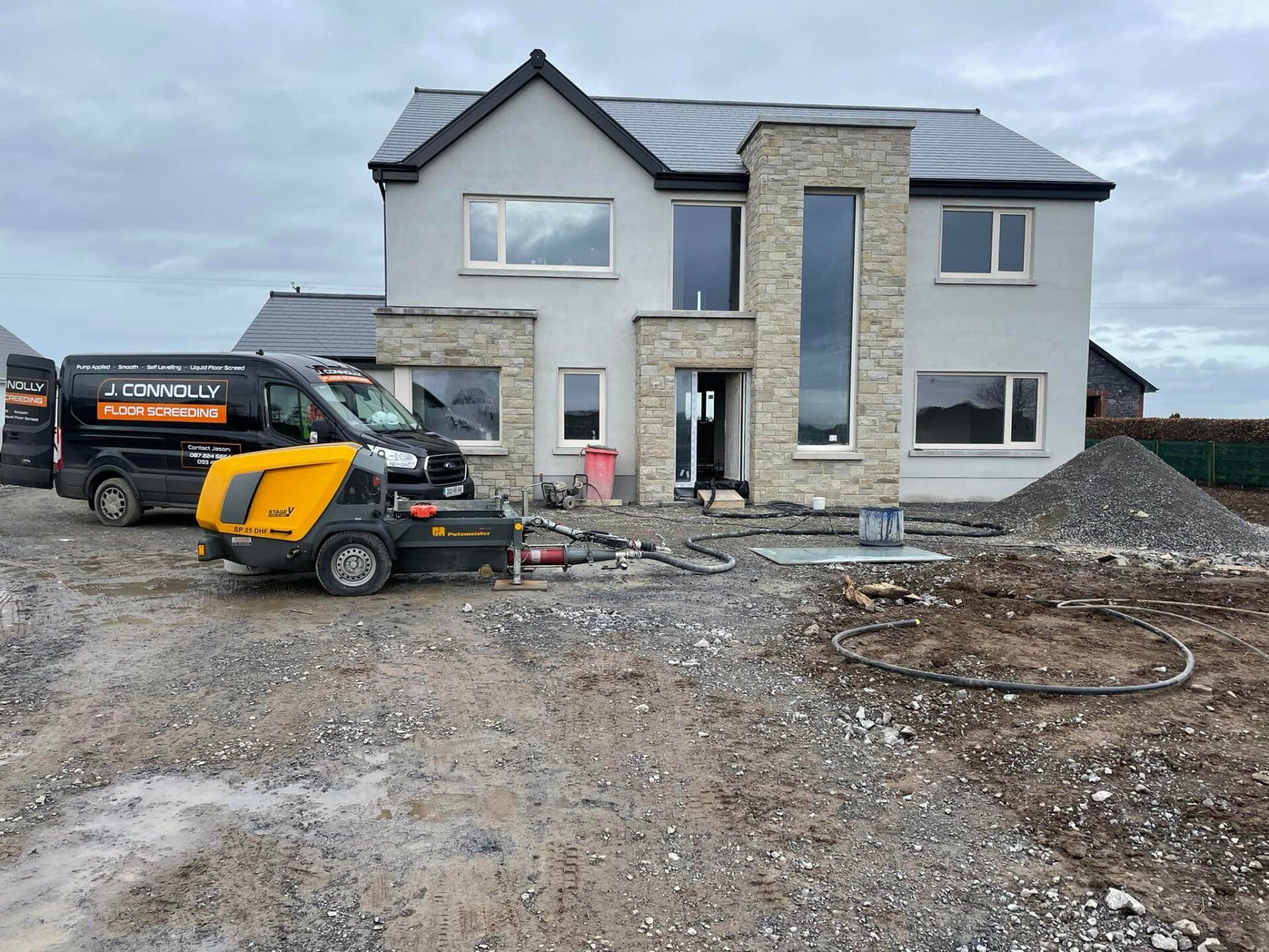 A house is being built with a concrete pump in front of it.