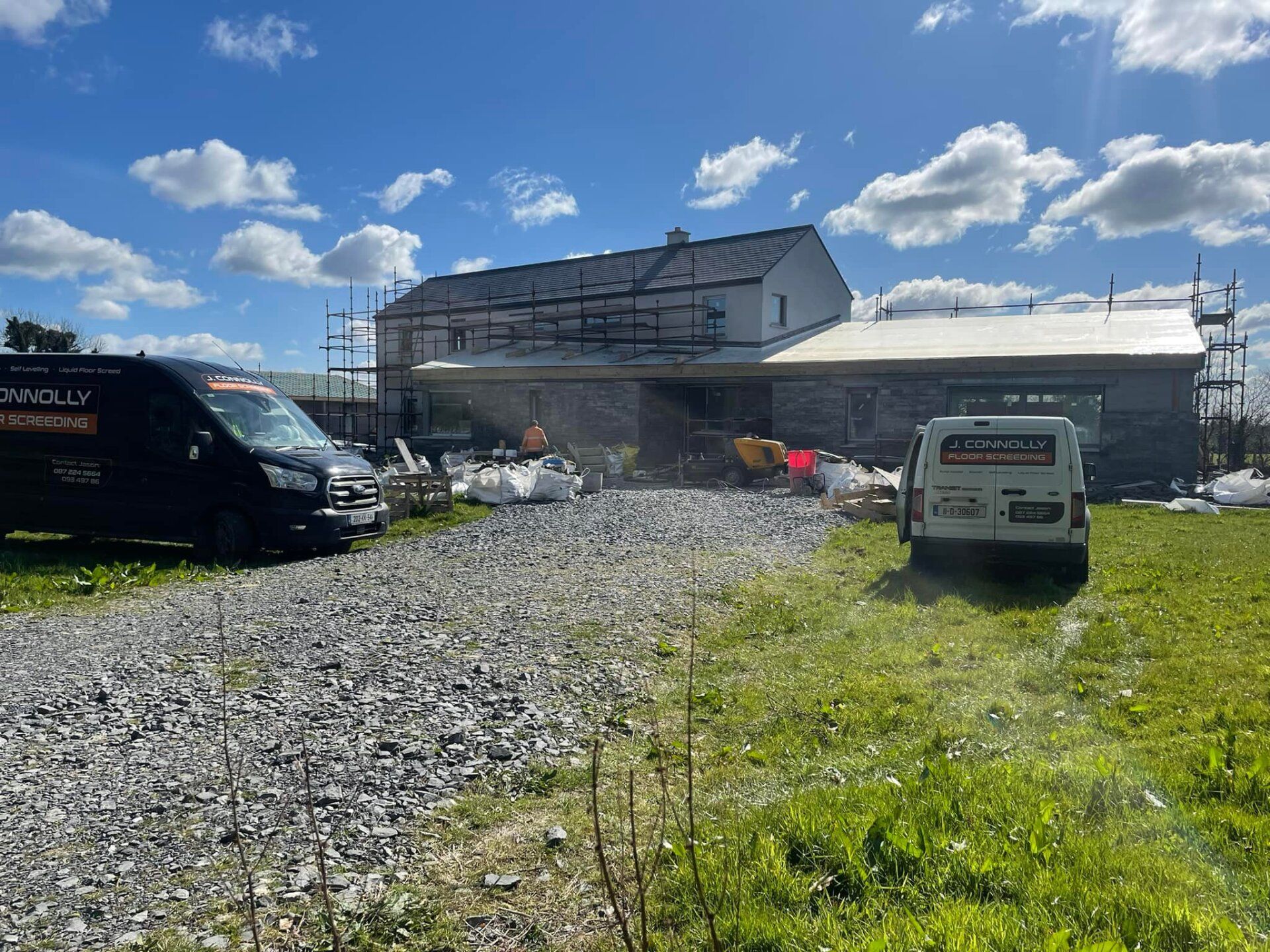 A group of vans are parked in front of a building under construction.