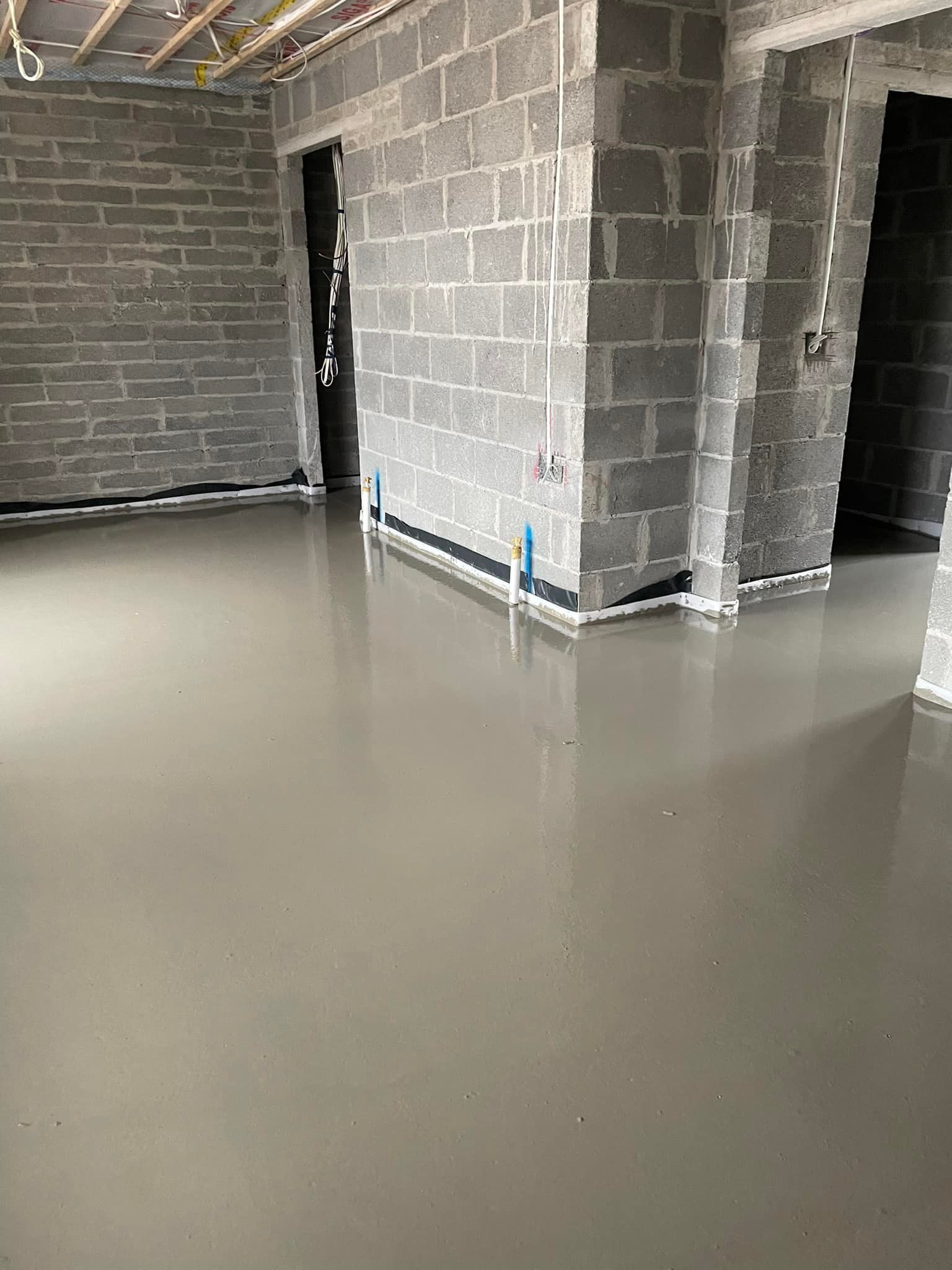 A room with a concrete floor and brick walls under construction.