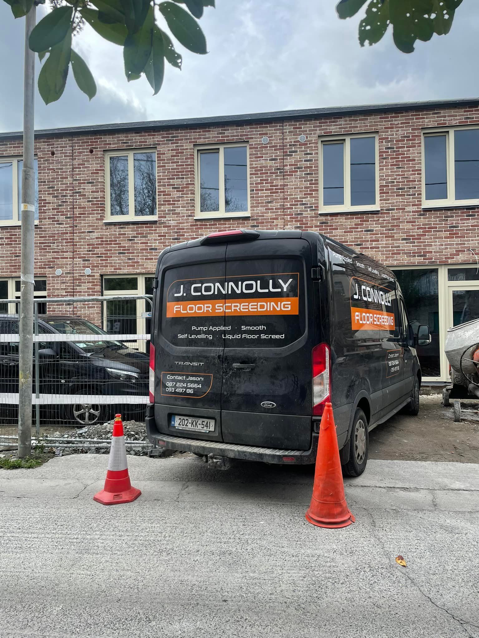 A black van is parked in front of a brick building.