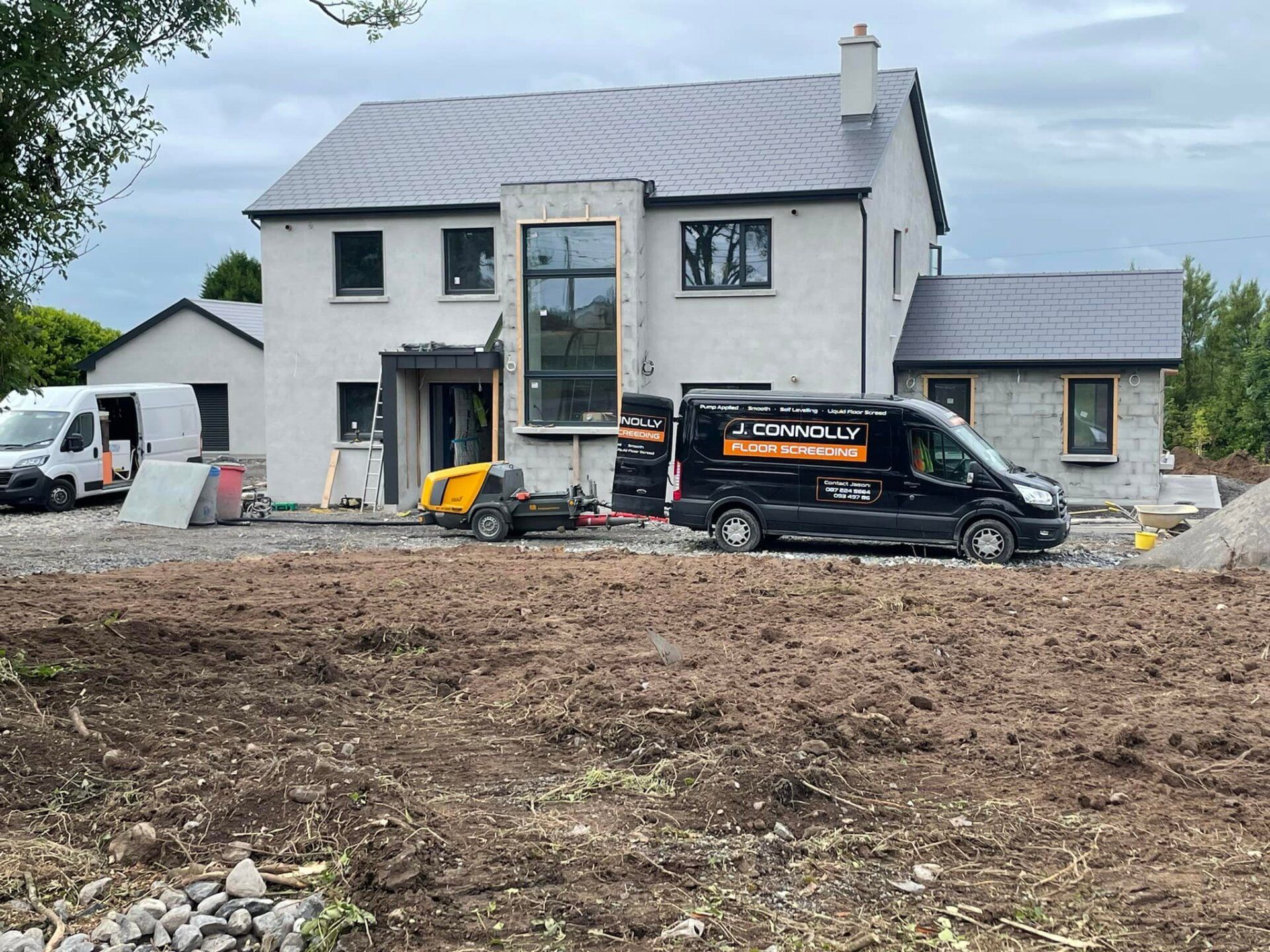 A black van is parked in front of a house under construction.
