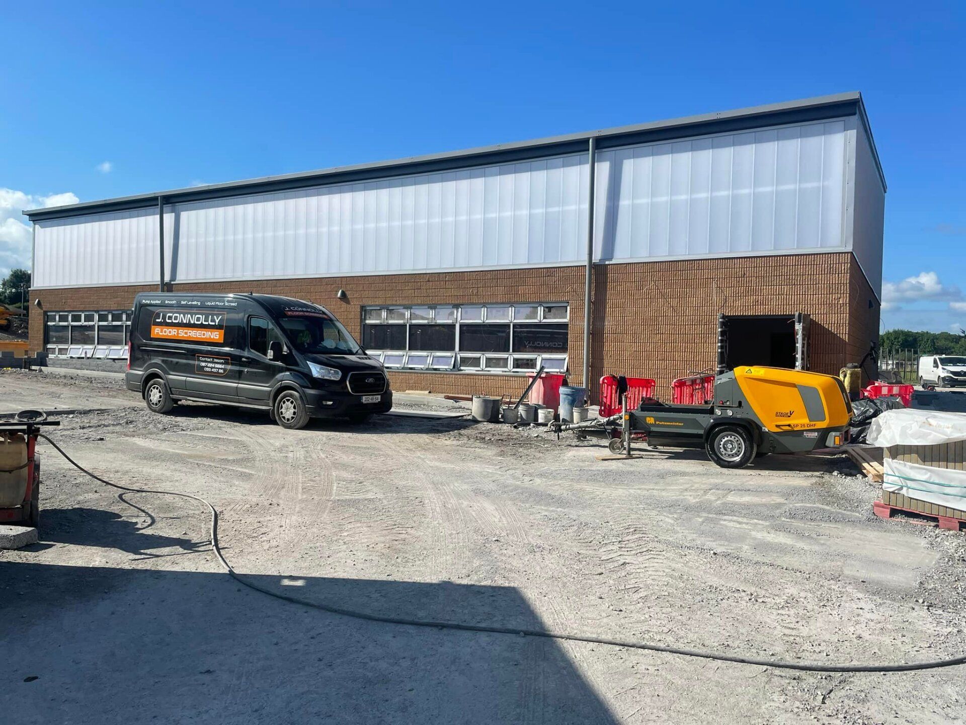Two vans are parked in front of a large building.