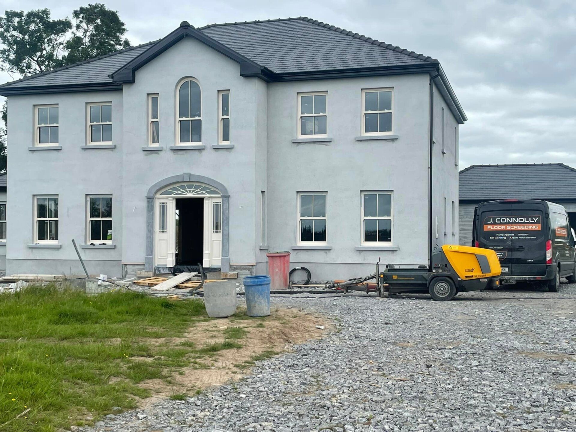 A white house with a black roof and a yellow van parked in front of it.