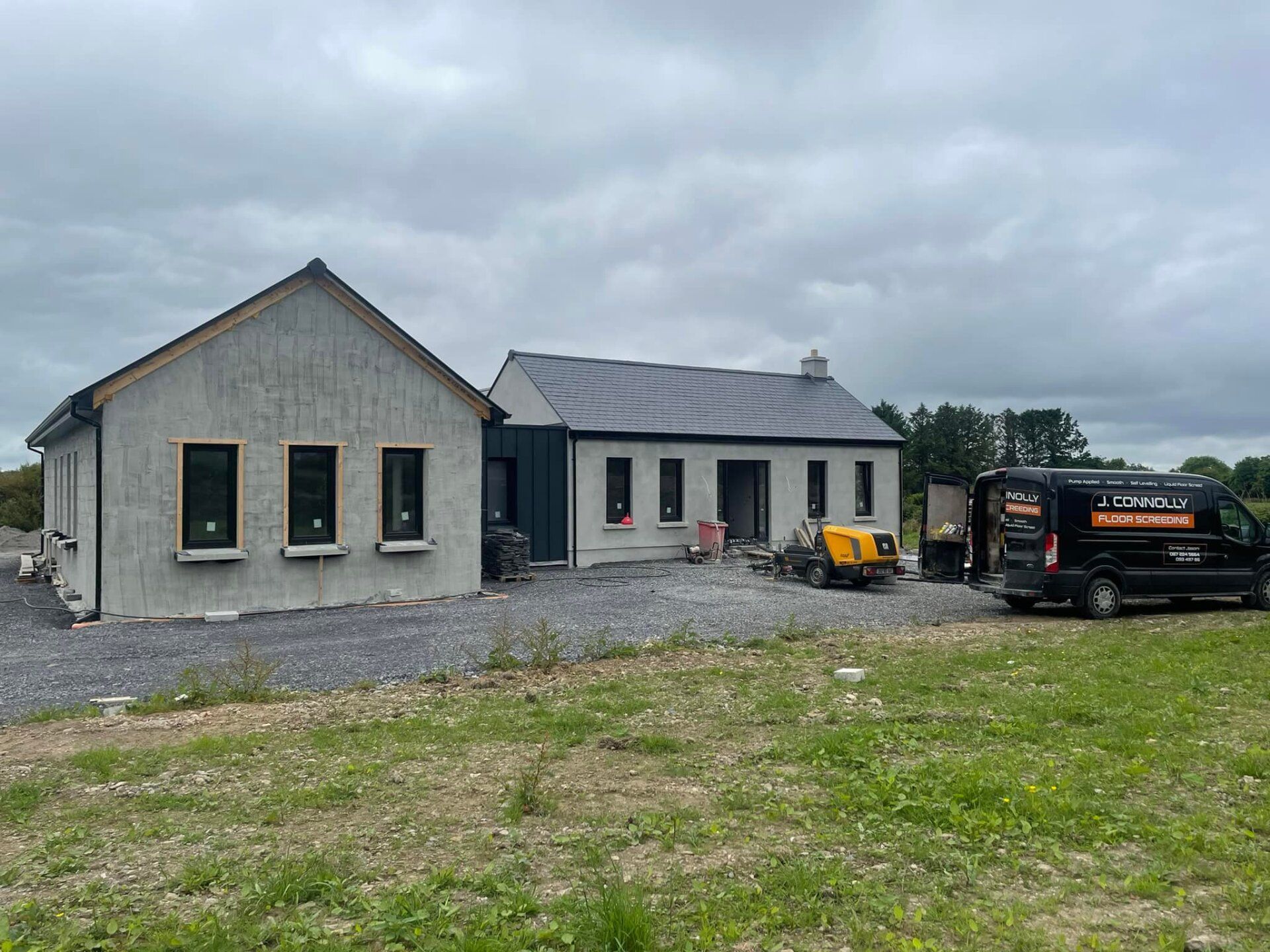 A black van is parked in front of a house under construction.