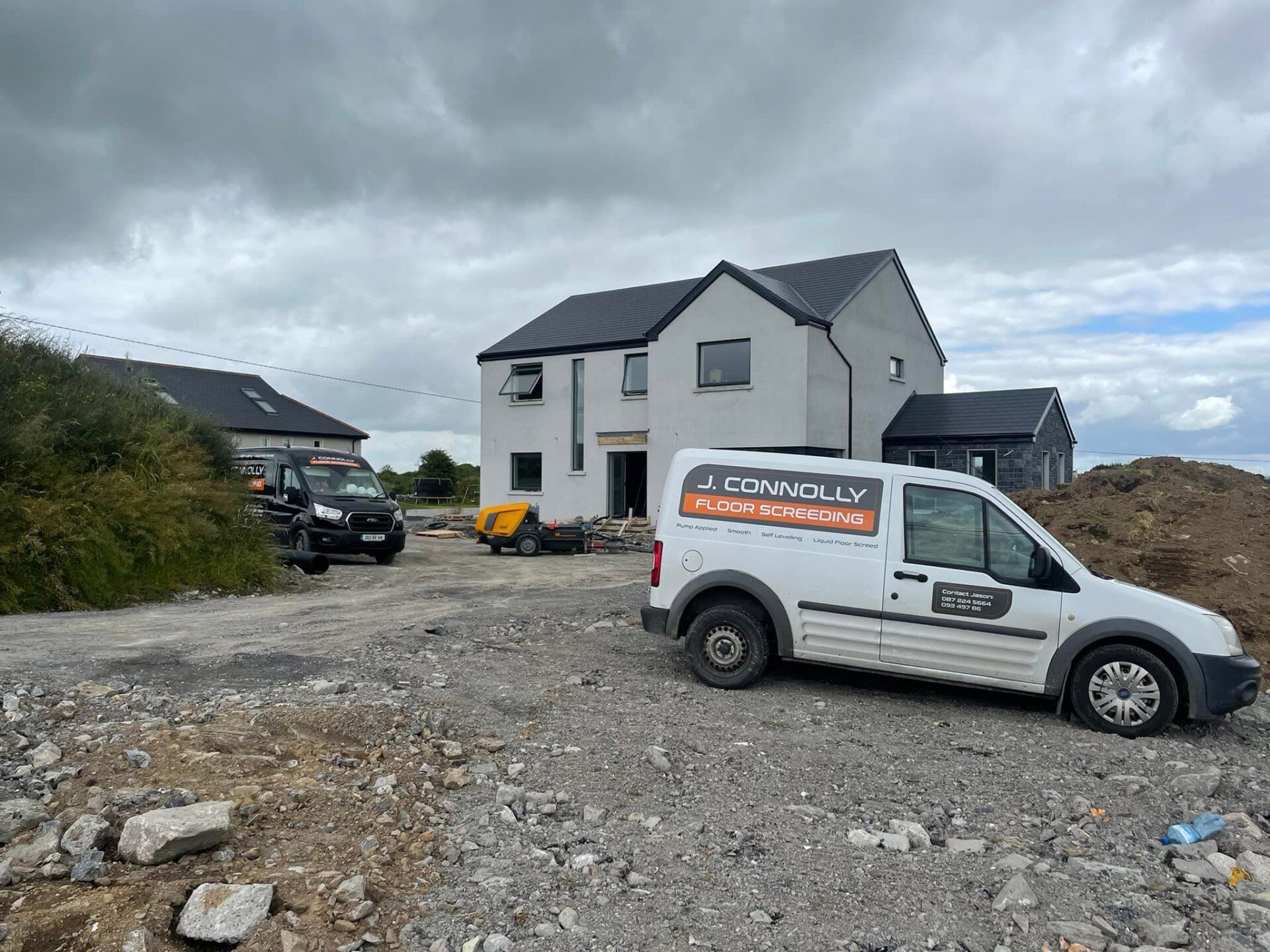 A white van is parked in front of a house under construction.