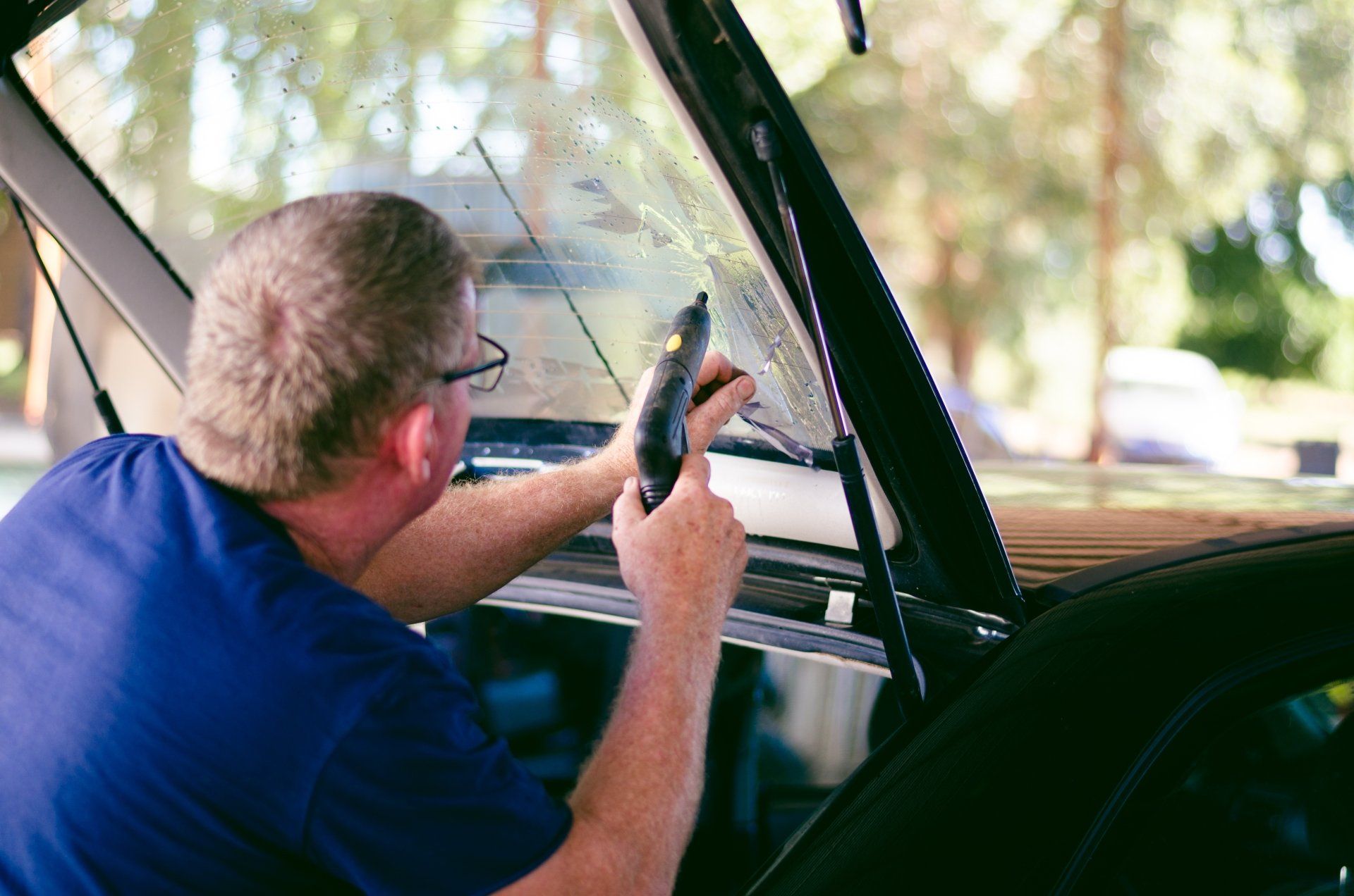 A man is working on the windshield of a car.