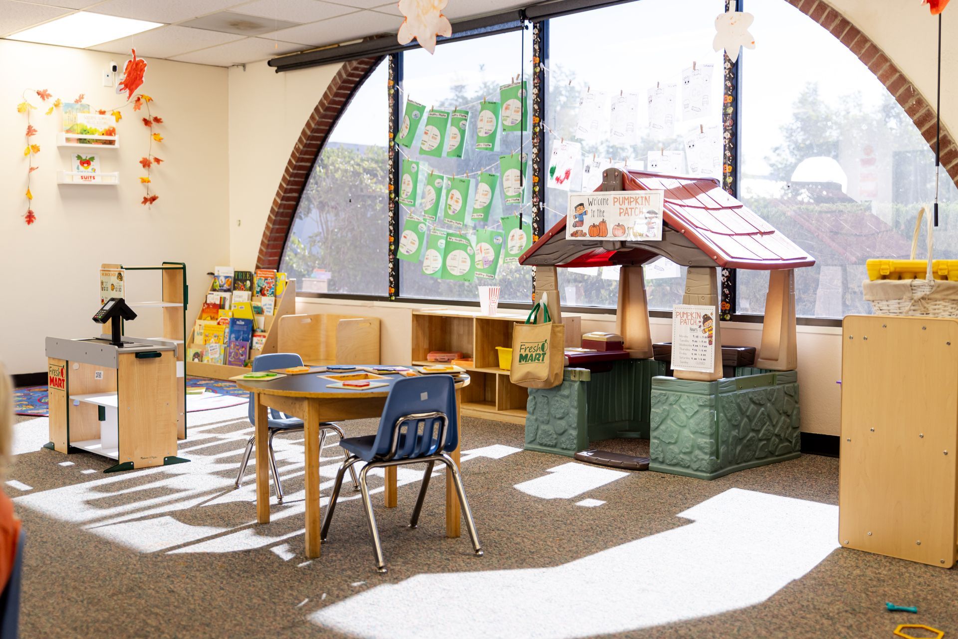 A classroom with a table and chairs and a playhouse