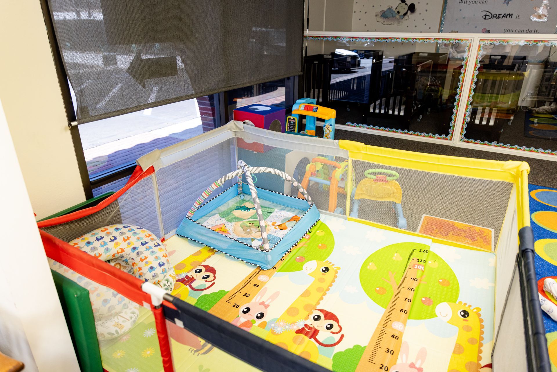 A baby play area with a crib and toys in a room.
