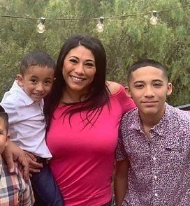 A woman is posing for a picture with two boys.