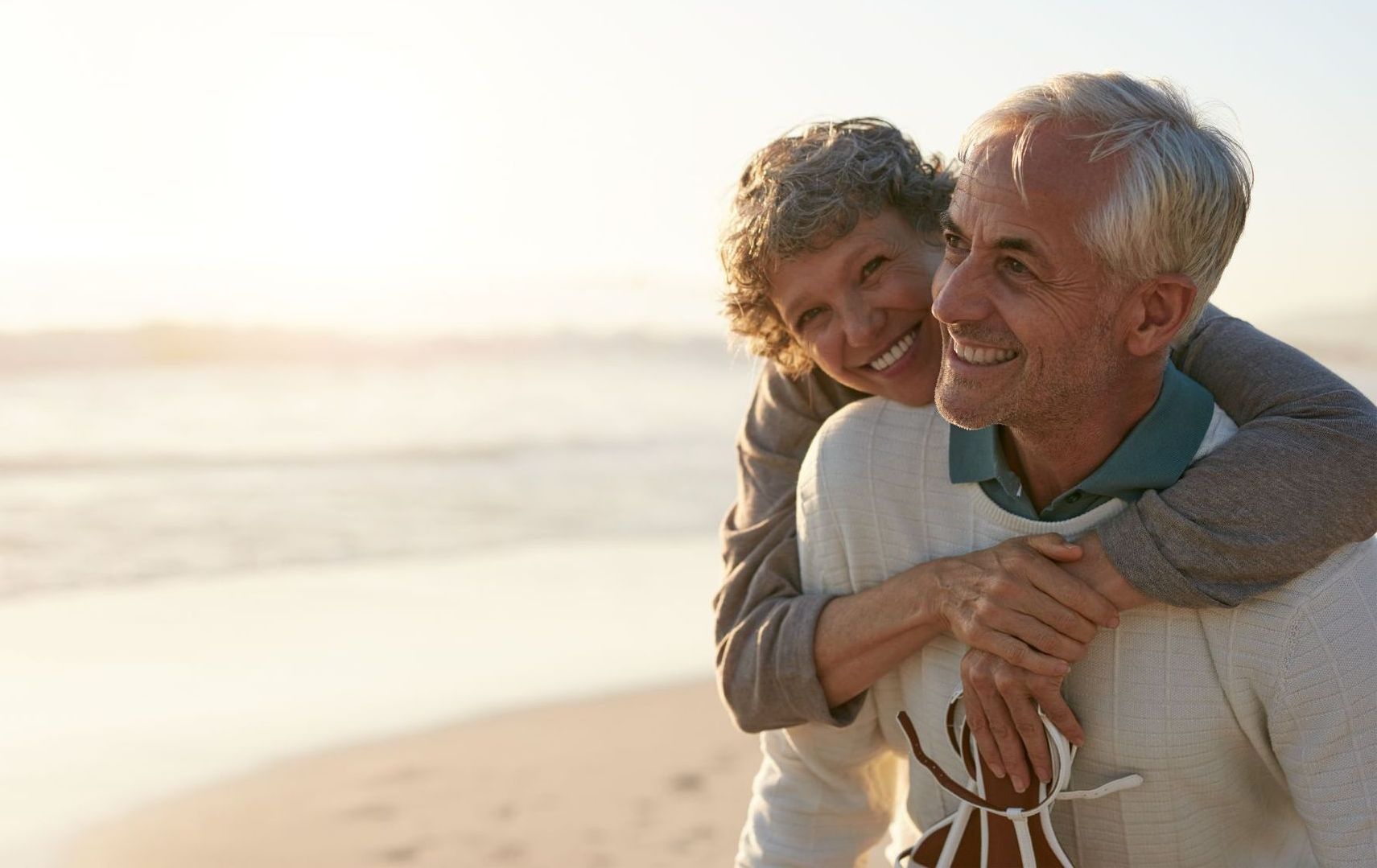 senior man and woman embracing on beach