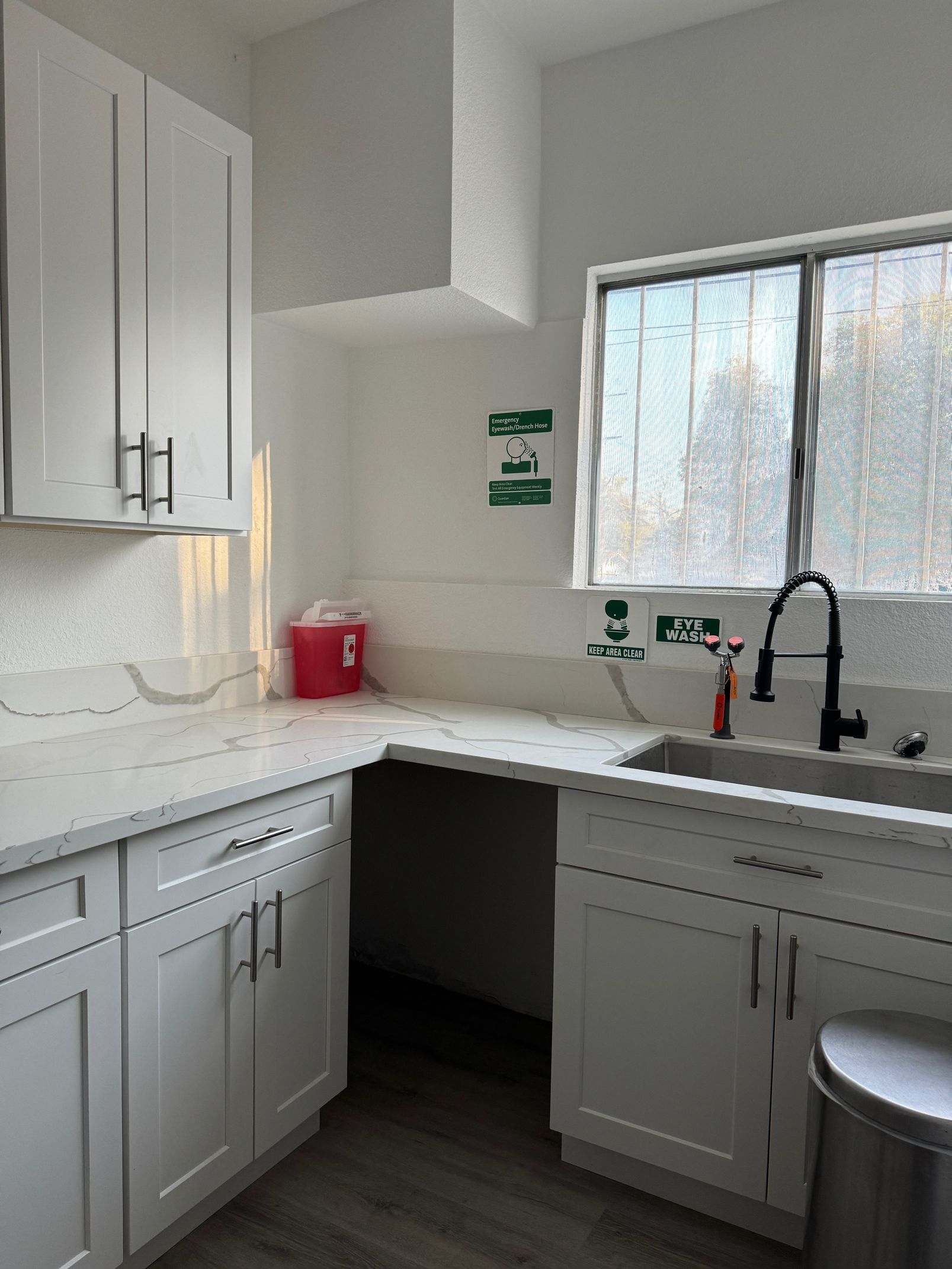 image of a room inside the clinic showing a sink below the window beside a kitchen counter and closets