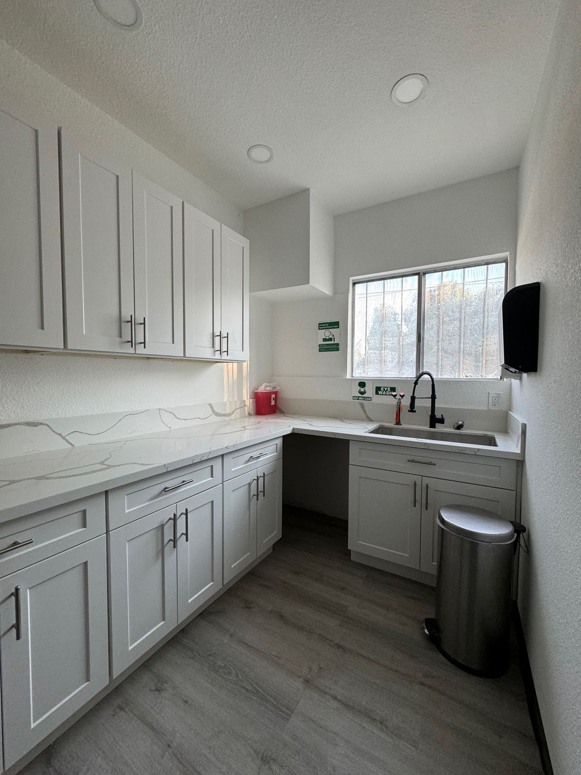 image of a room inside the clinic showing a sink below the window beside a kitchen counter and closets