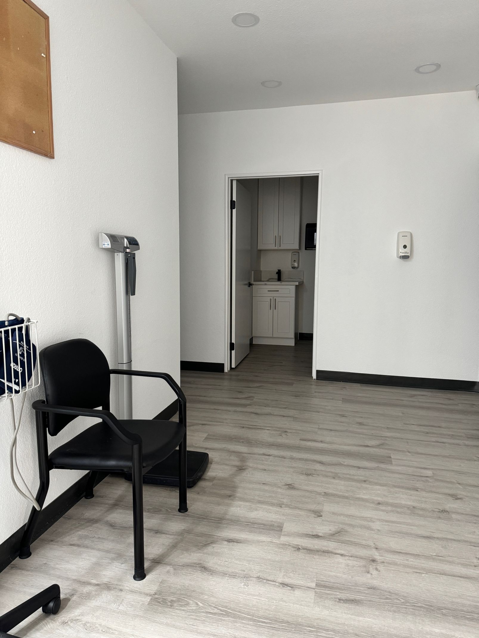a room inside the clinic where they take the patient's vitals. a black chair on the left beside the weighing scale and comfort room