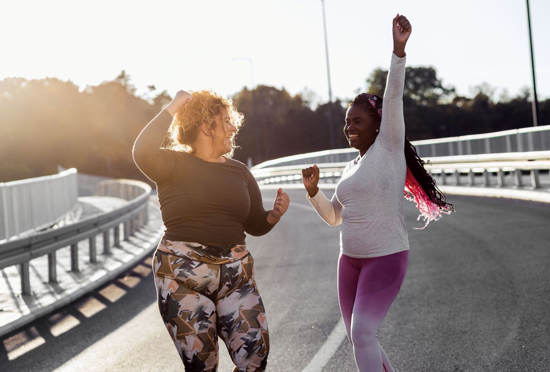 two overweight women in athletic wear celebrating after weight loss