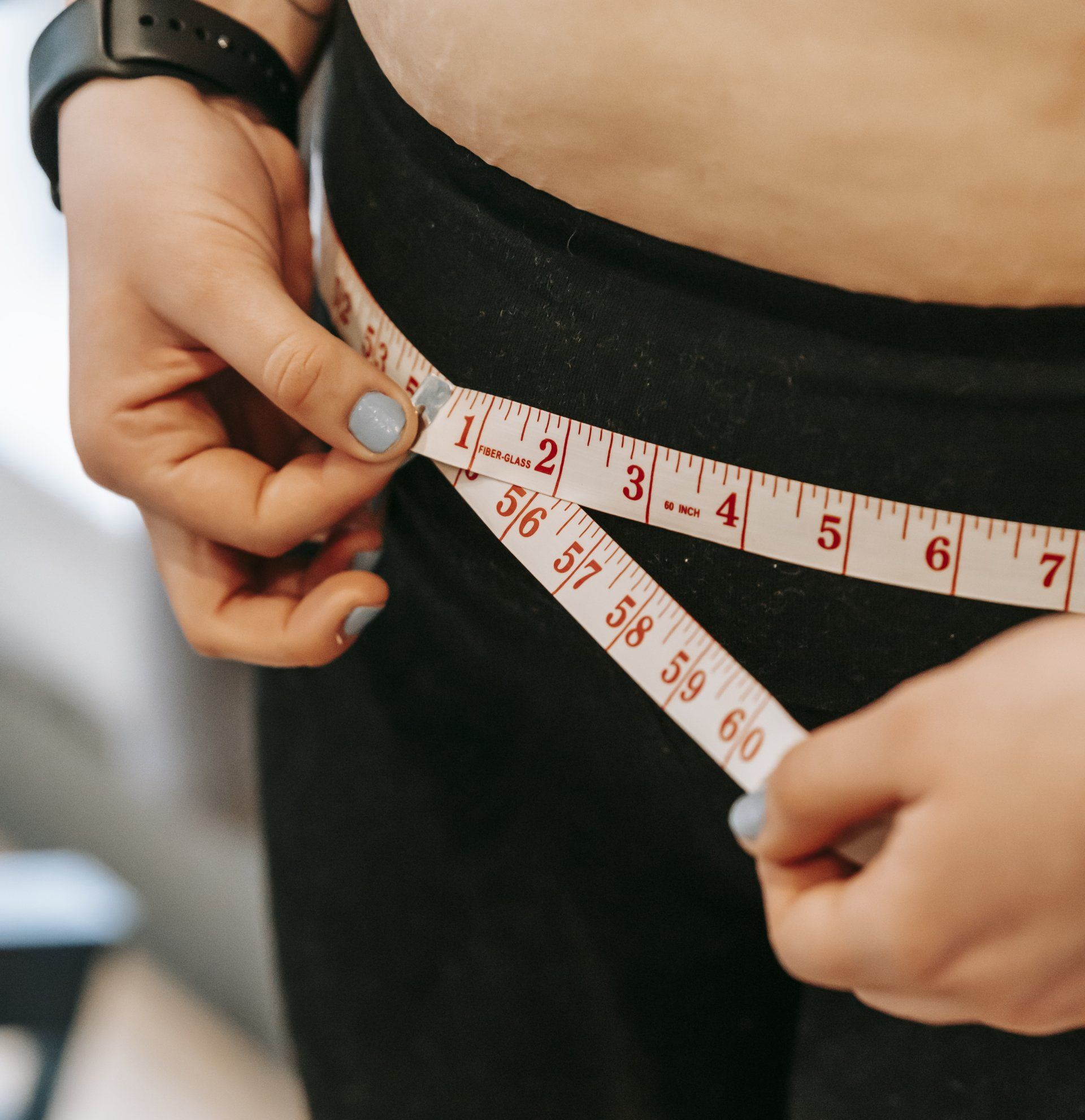 a woman is measuring her waist with a tape measure
