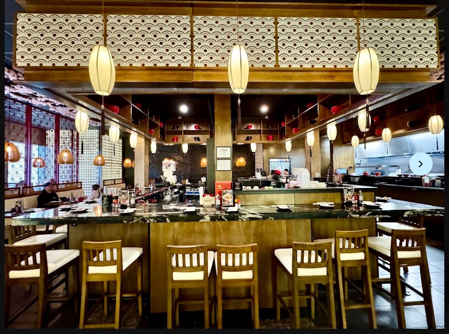 A restaurant with tables and chairs and a long counter.