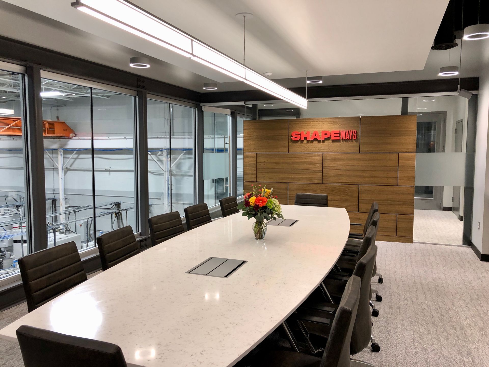 A conference room with a long table and chairs and a vase of flowers.