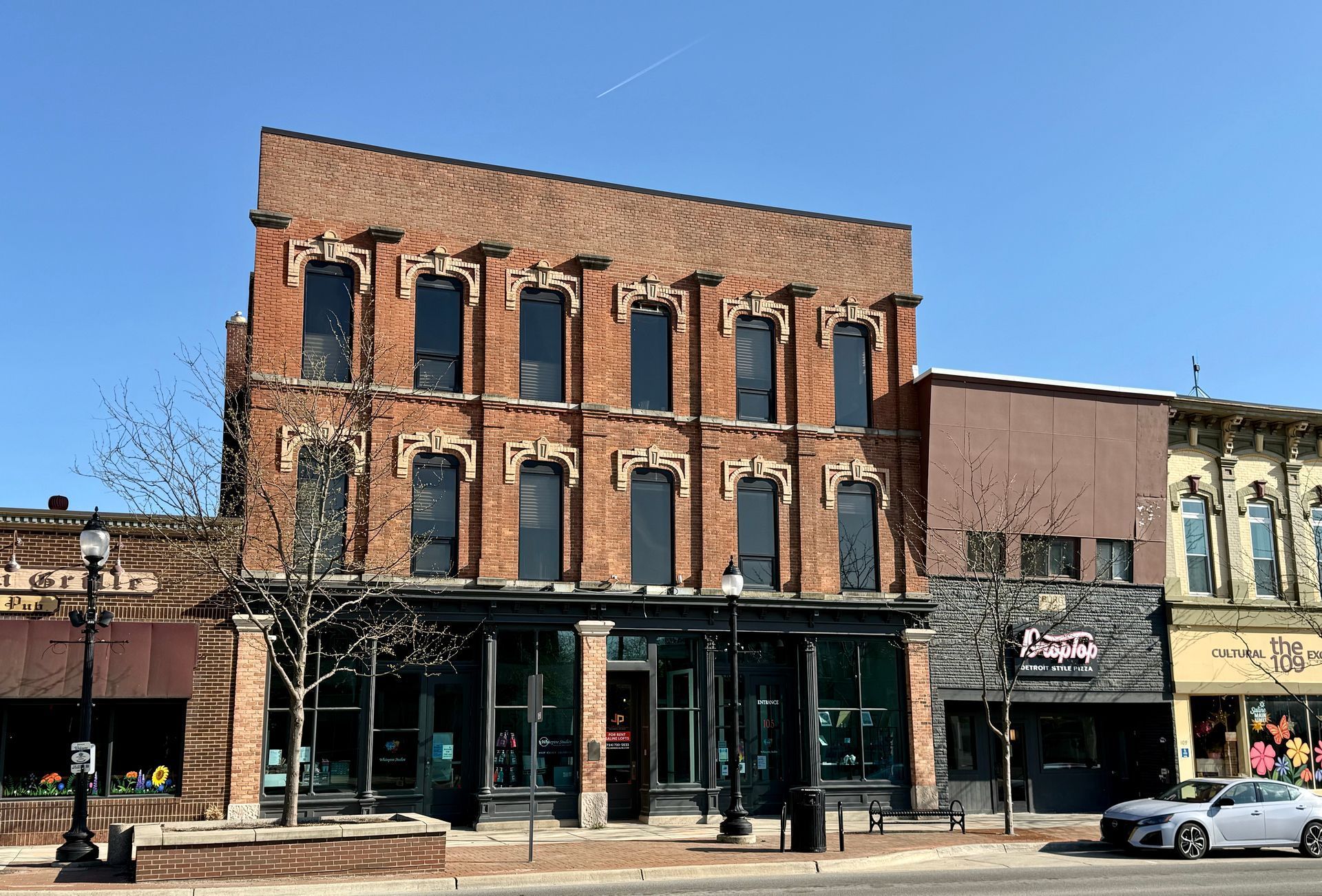A large brick building is sitting on the corner of a city street.