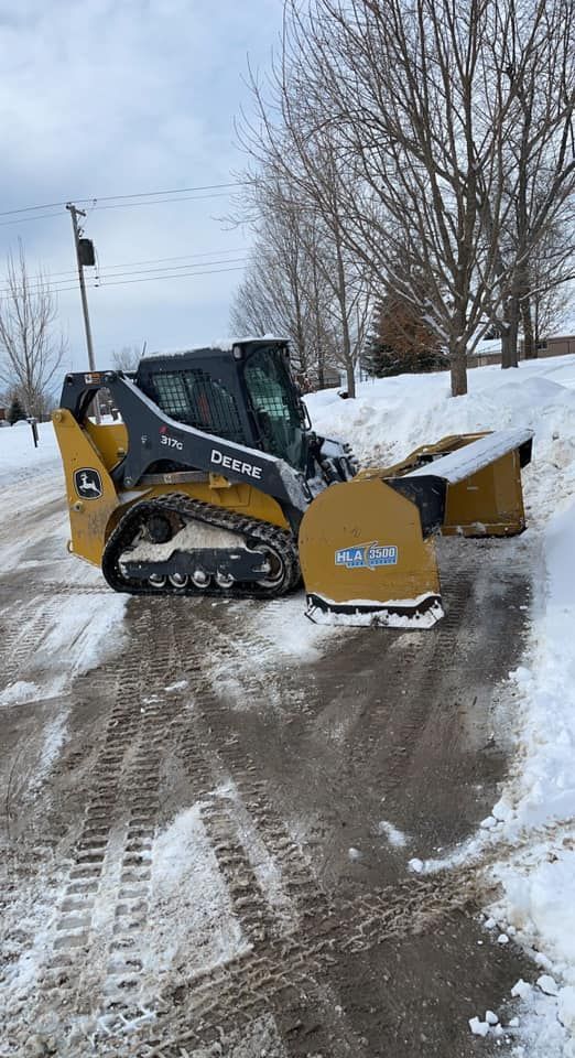 A snow plow is clearing snow from the side of a road.