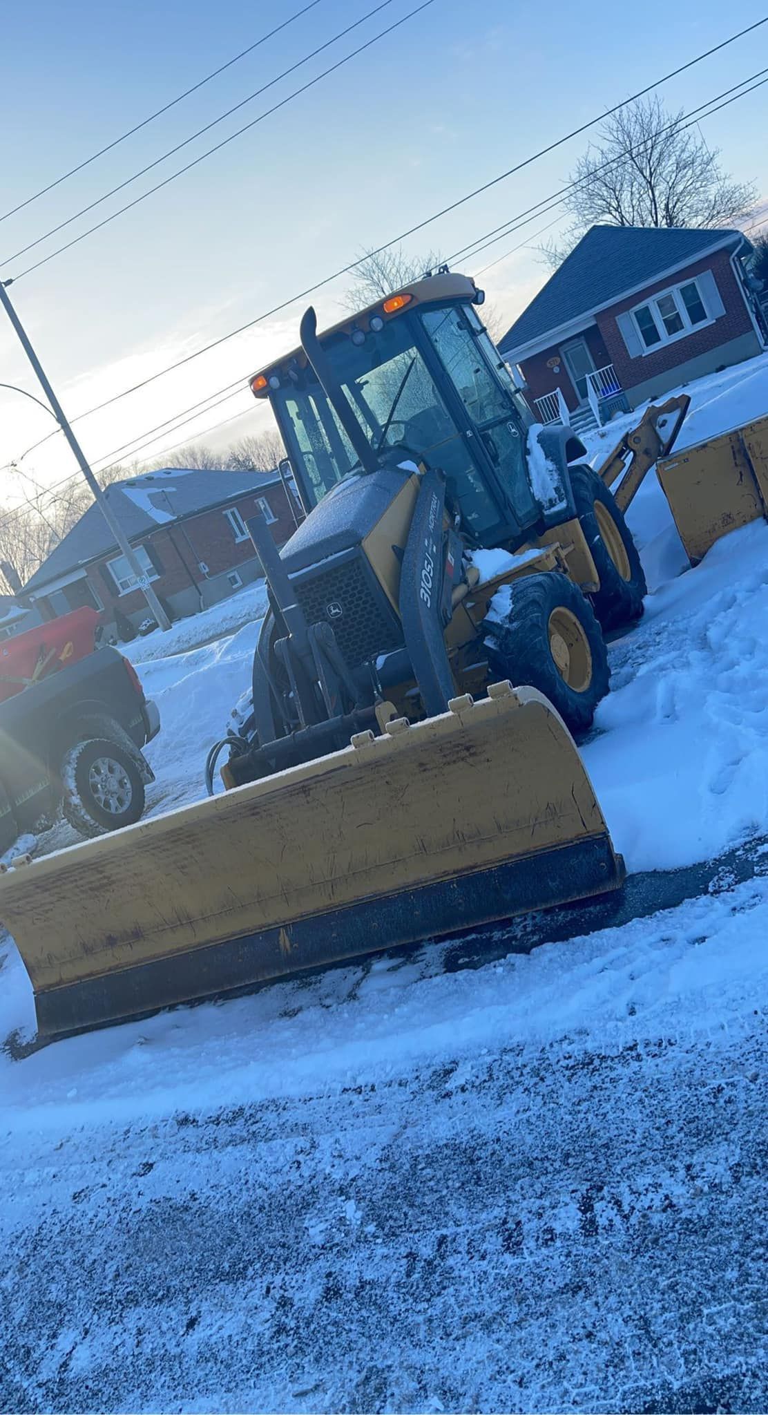 A snow plow is plowing snow on the side of the road.
