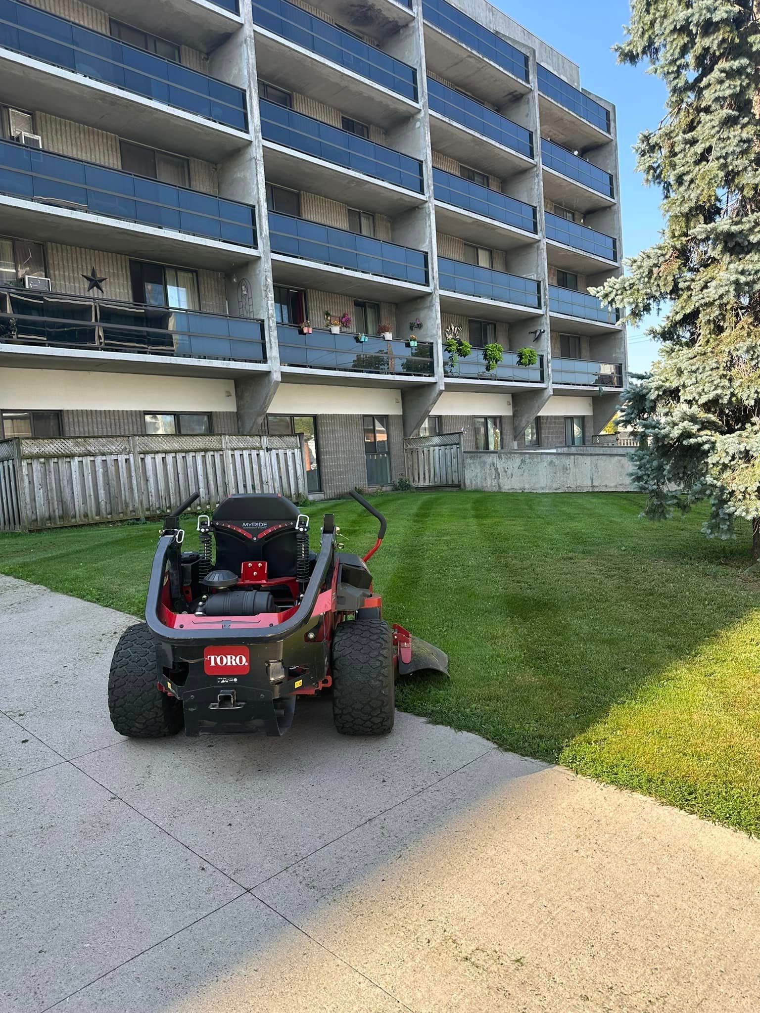 A lawn mower is cutting grass in front of a building.