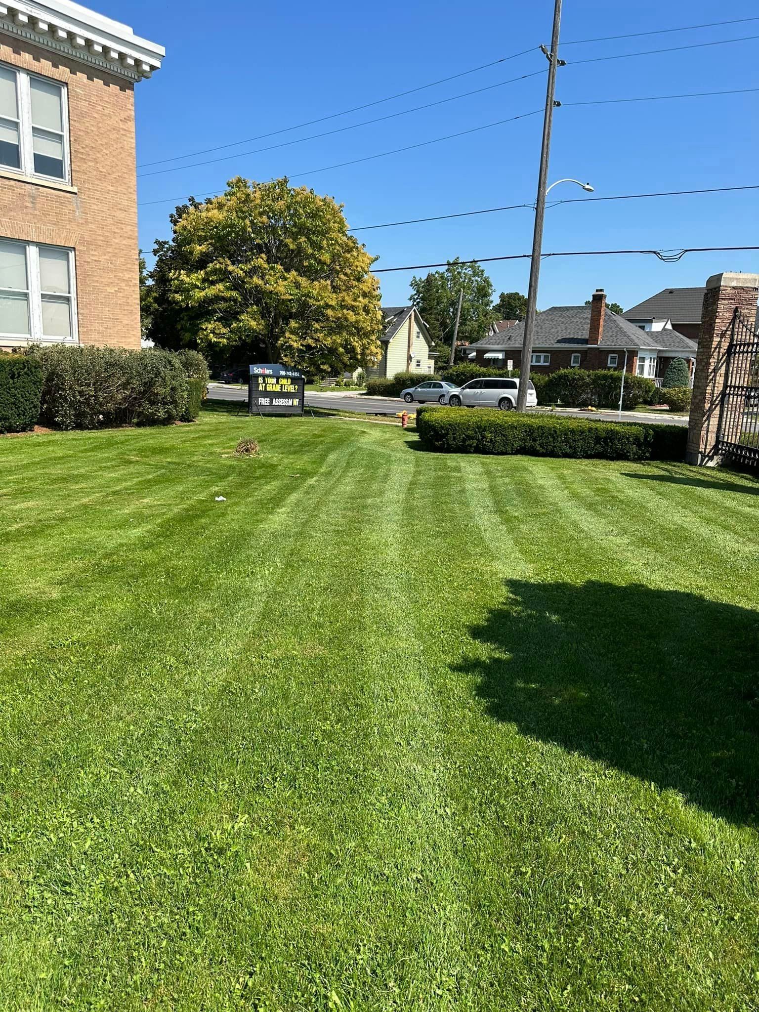 A lush green lawn with a brick building in the background.