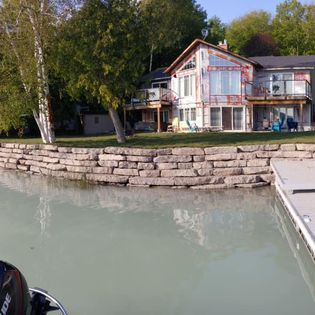 A boat is docked in front of a large house next to a body of water.