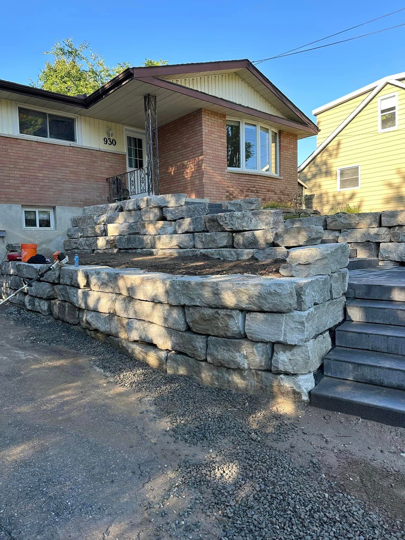 A house with a stone wall and stairs in front of it.