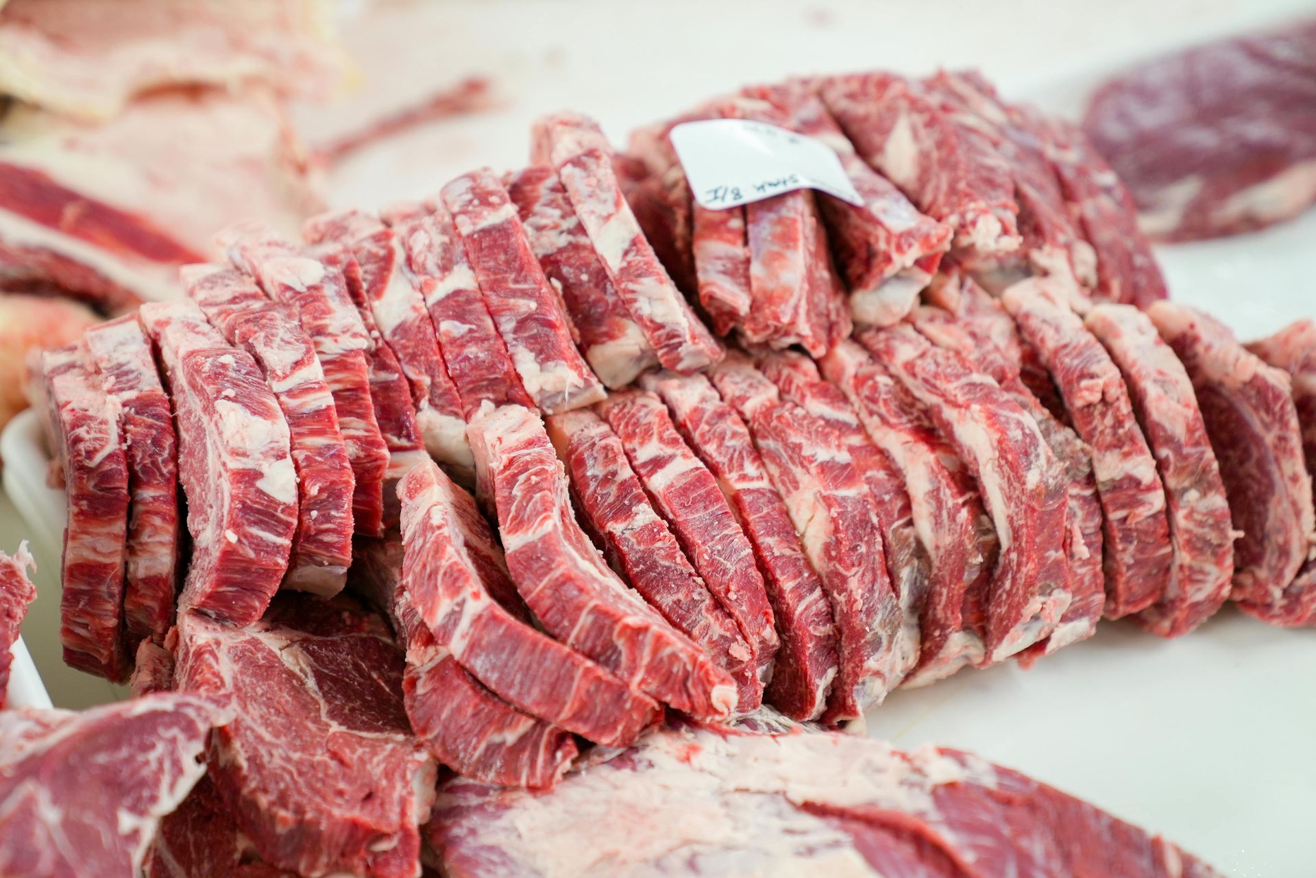 Sliced red beef on a butcher's counter, ready for sale.