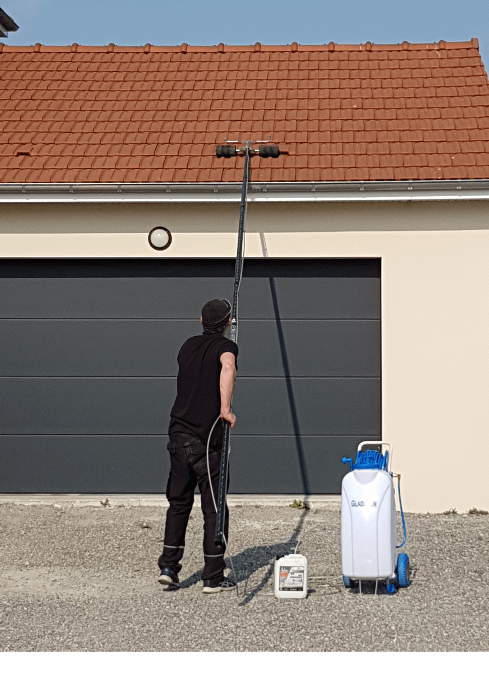 Un homme nettoie le toit d'un garage avec une perche.