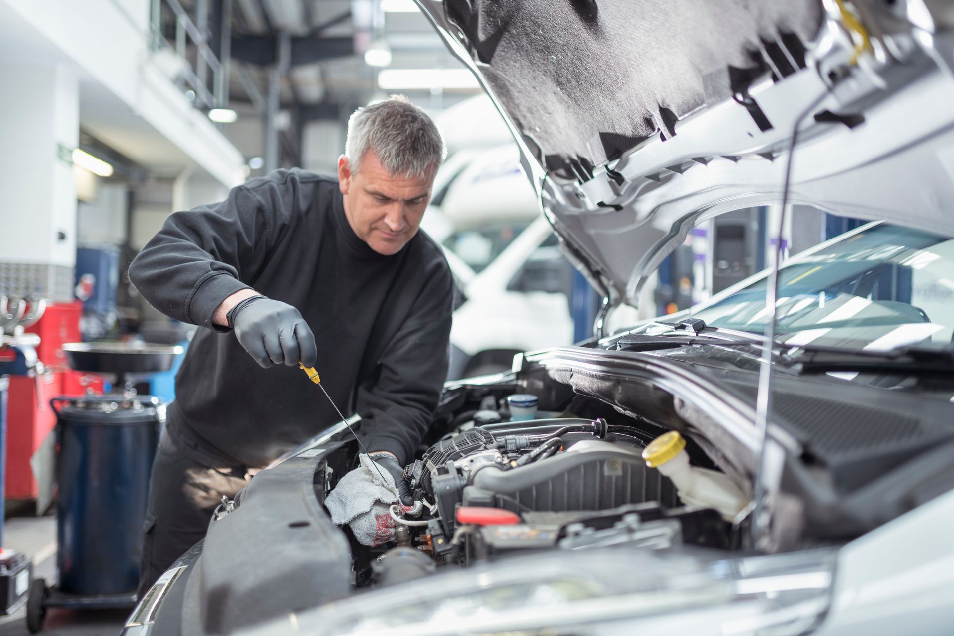 A man is working on the engine of a car in a garage.