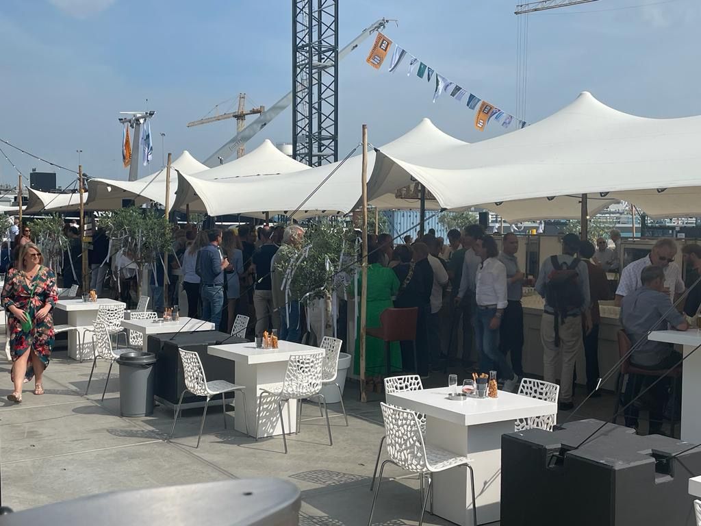 Een evenement in de openlucht met witte tenten, tafels en een grote menigte.