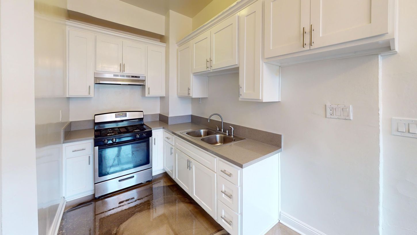 White kitchen with cabinets, stove, sink, and countertops.