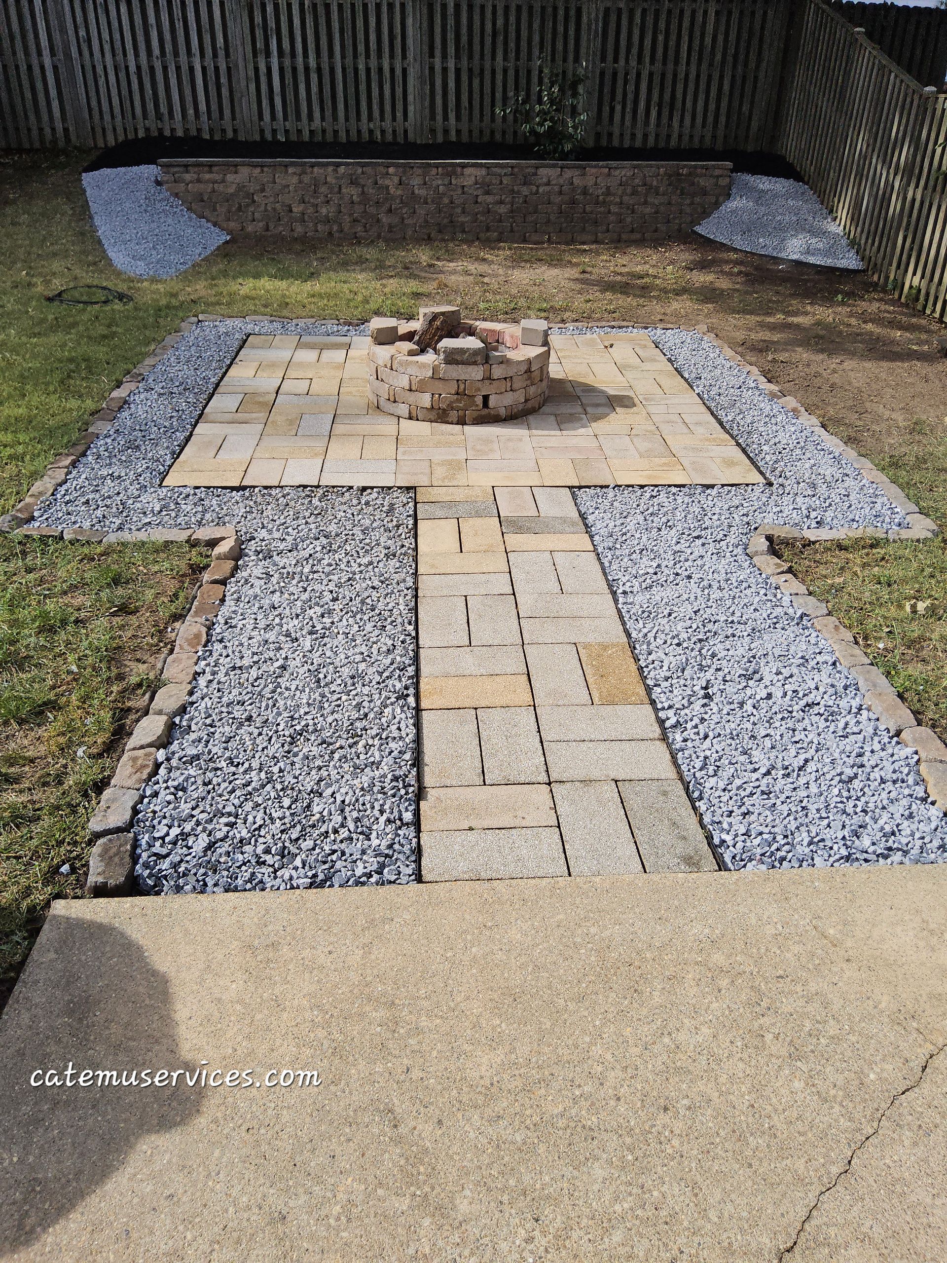 Backyard patio with fire pit, brick pathway, and gravel border.