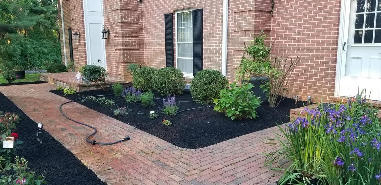 Brick pathway leading to a brick home with landscaped flower beds and shrubs.