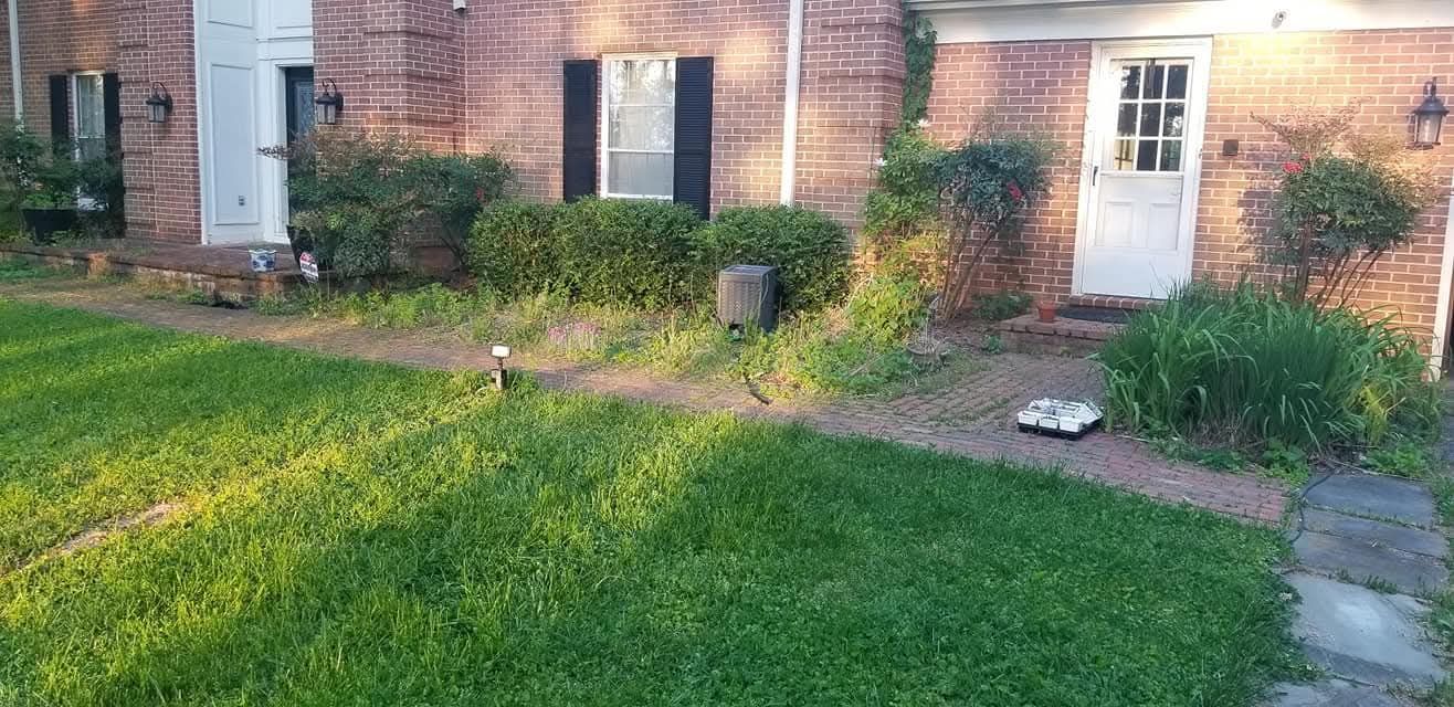 Brick building with green lawn, bushes, and a pathway leading to a white door.