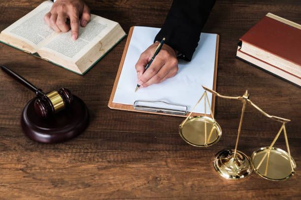 A person is writing on a clipboard next to a judge 's gavel and scales of justice.