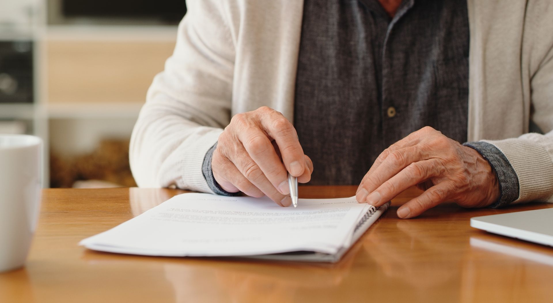 A man is sitting at a table writing on a piece of paper.