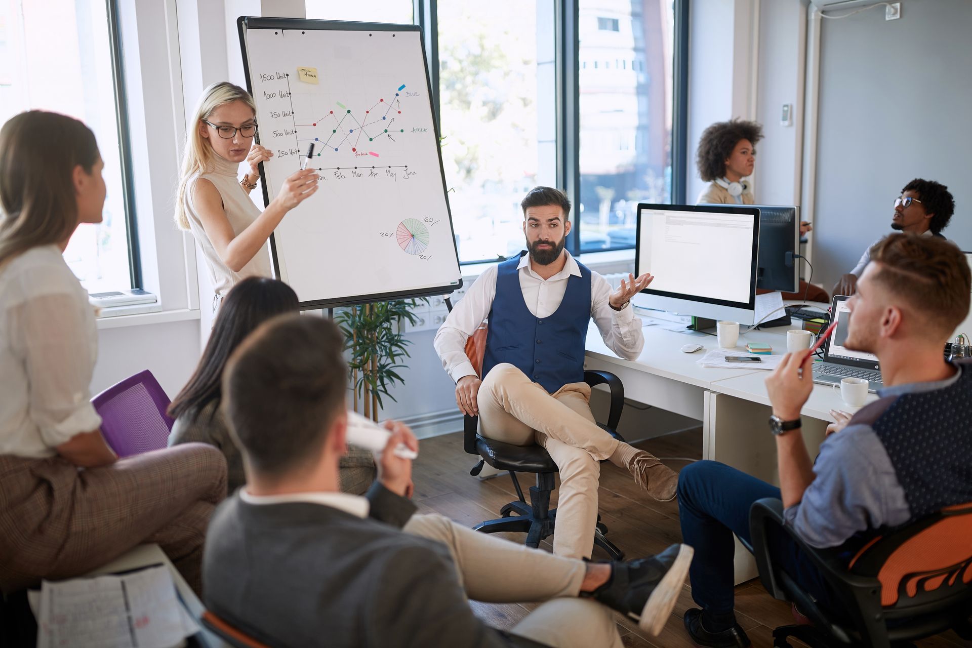 A woman is giving a presentation to a group of people in an office.