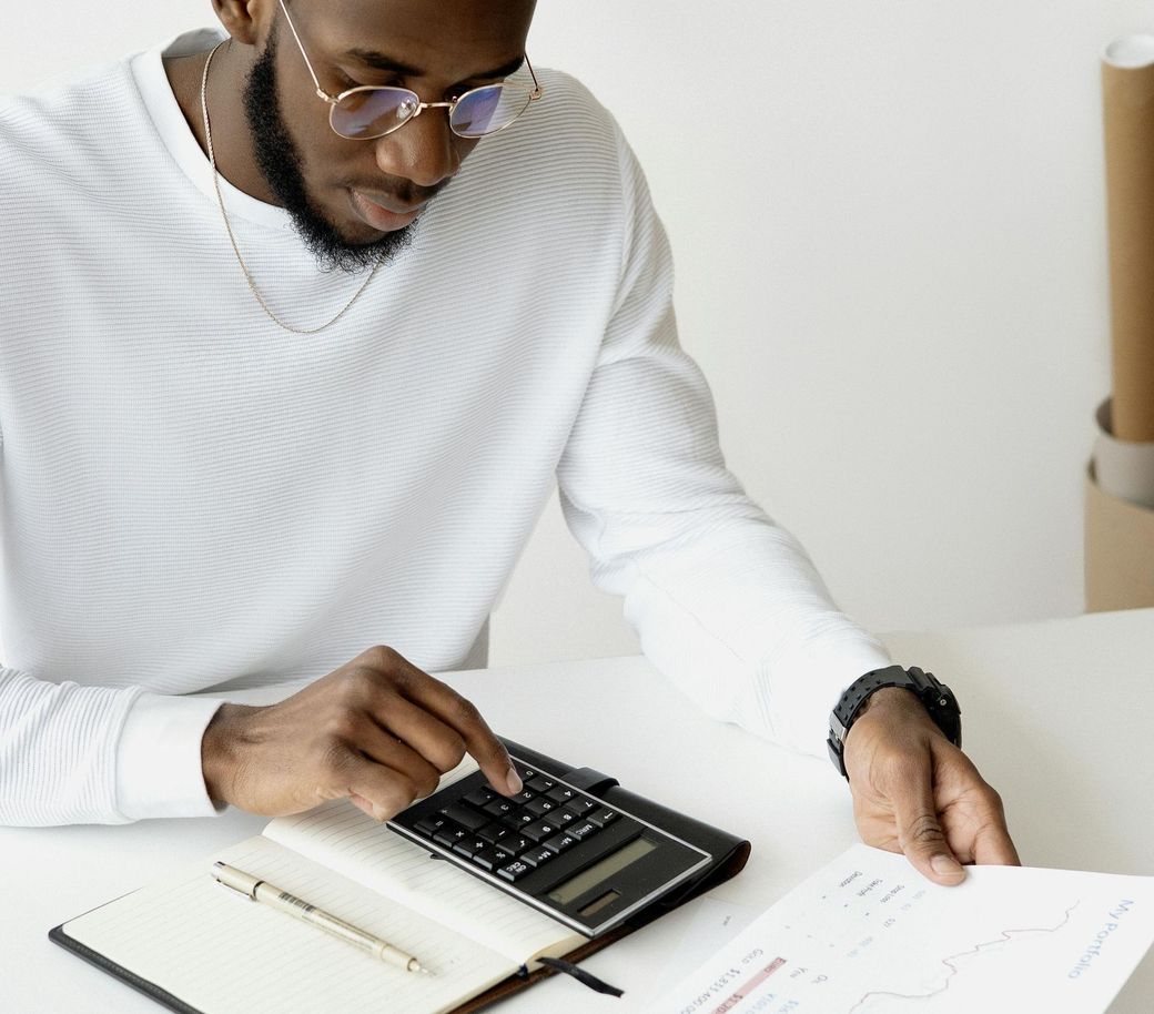 A man is sitting at a table using a calculator.