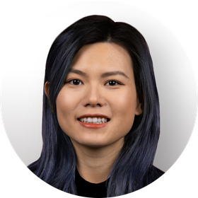 A woman with long hair is smiling in a circle with trees in the background.