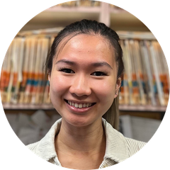 A woman is smiling in a circle in front of a bookshelf.