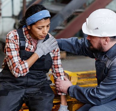 A man in a hard hat is helping a woman with a bandage on her arm.