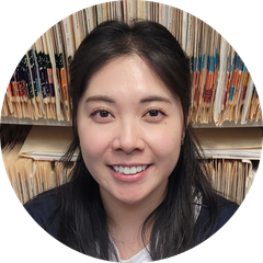 A woman is smiling in a circle in front of a bookshelf.