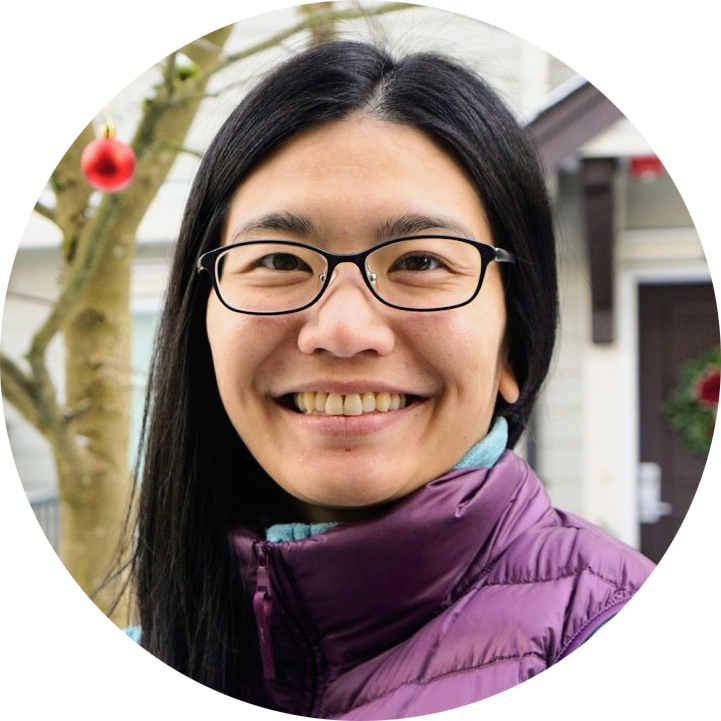 A woman with long hair is smiling in a circle with trees in the background.