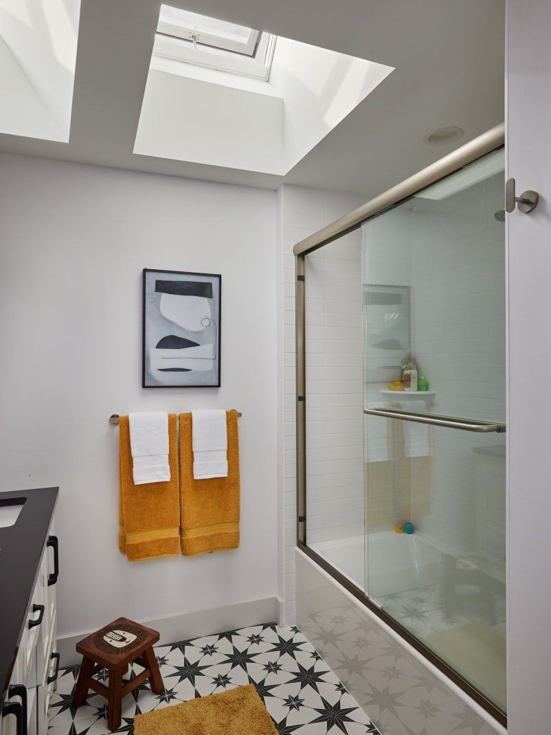 Bathroom with skylights, shower, towels, and decorative tile flooring.