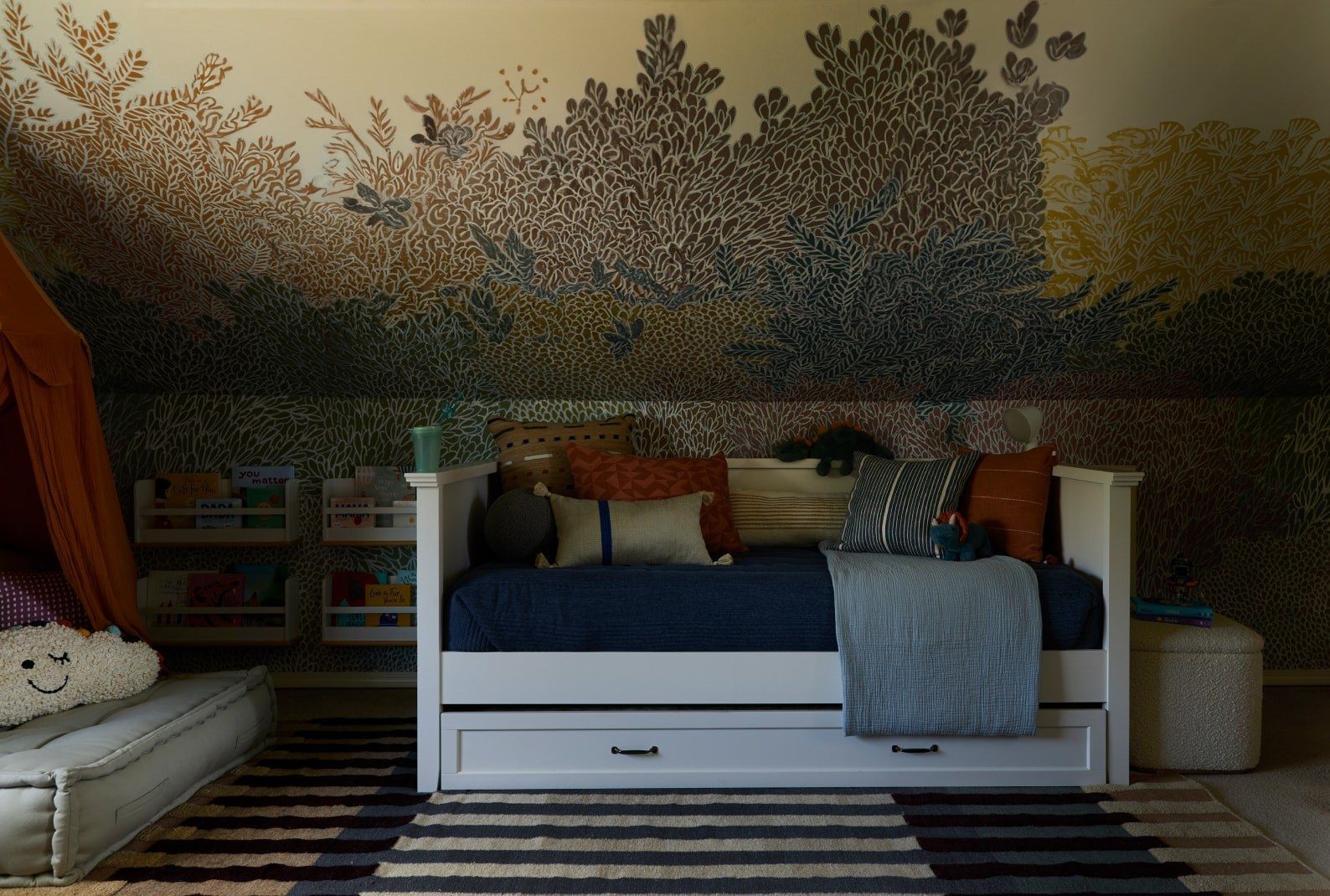 Bedroom with forest-themed wallpaper, a daybed, storage, and a rug.
